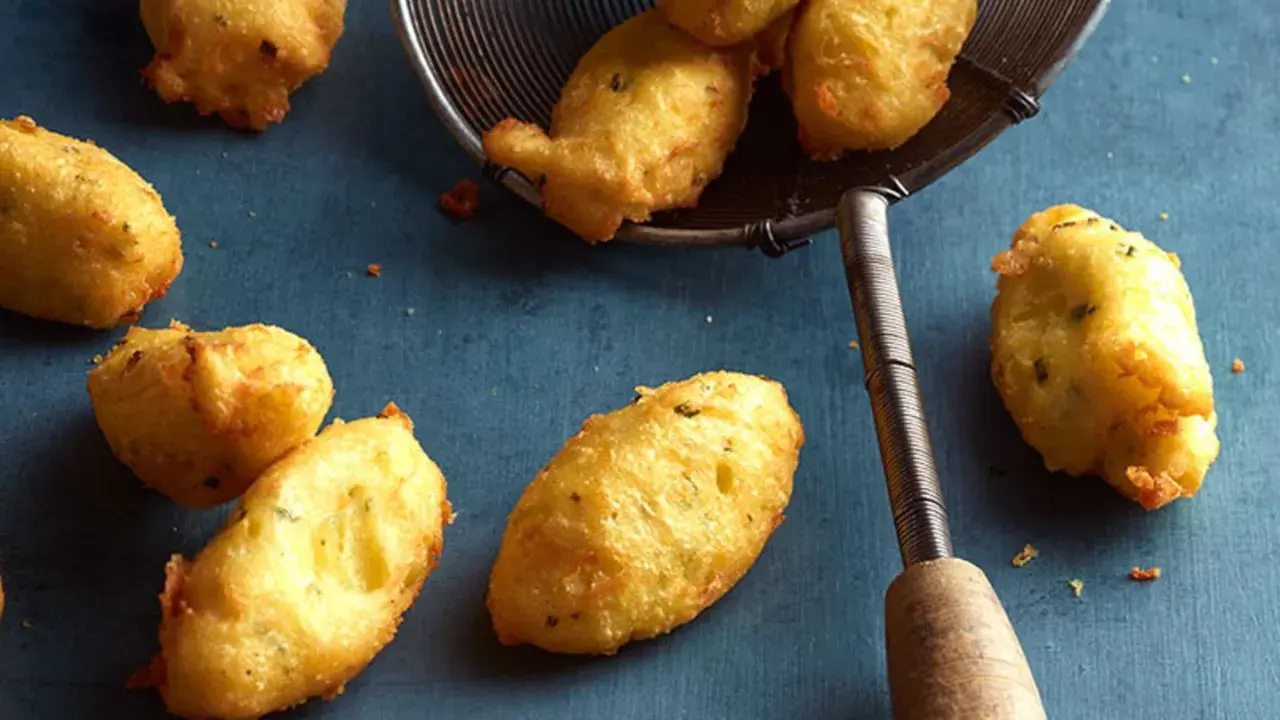 Goldbraune Dauphine Kartoffeln, frisch frittiert und auf einem Abtropfsieb. Ein Genuss für jeden Kartoffelliebhaber.