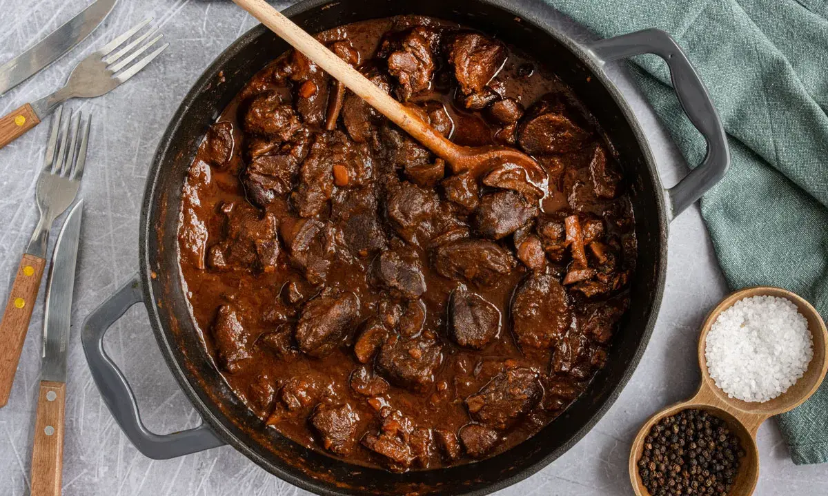 Herzhafter Rehgulasch in dunkler Sauce, bereit zum Schmoren. Die Frage "reh gulasch wie lange schmoren" wird hier visuell beantwortet: lange und langsam für zartes Fleisch.
