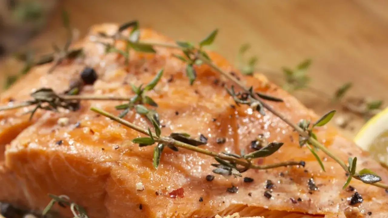 Delicioso salmón al horno con hierbas frescas y pimienta negra, listo para servir.