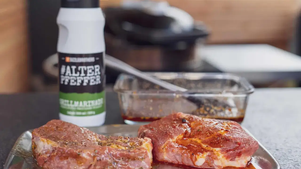Zwei Steaks liegen auf einem Blech, bereit für die beste Steak Marinade. Daneben eine Flasche "#ALTER PFEPPER" Grillmarinade.