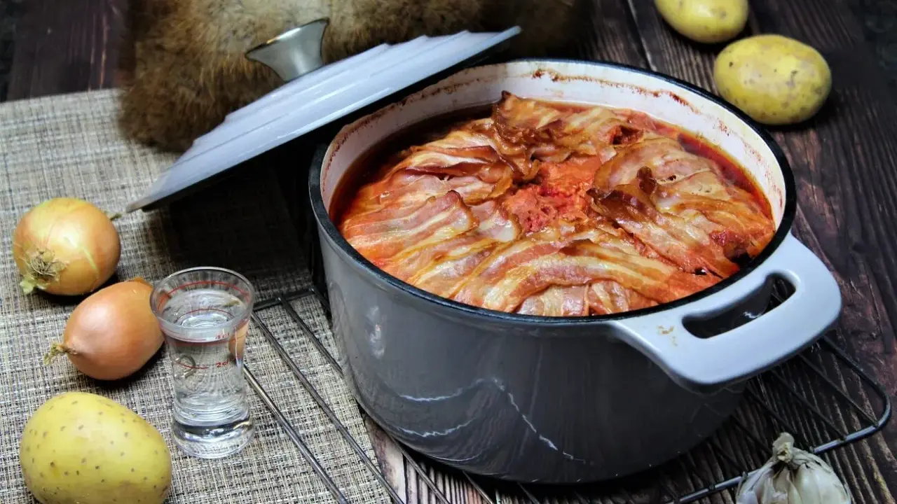 Herzhaftes russisches Essen: Ein Eintopf mit Speck überbacken, dazu Kartoffeln, Zwiebeln und Knoblauch.
