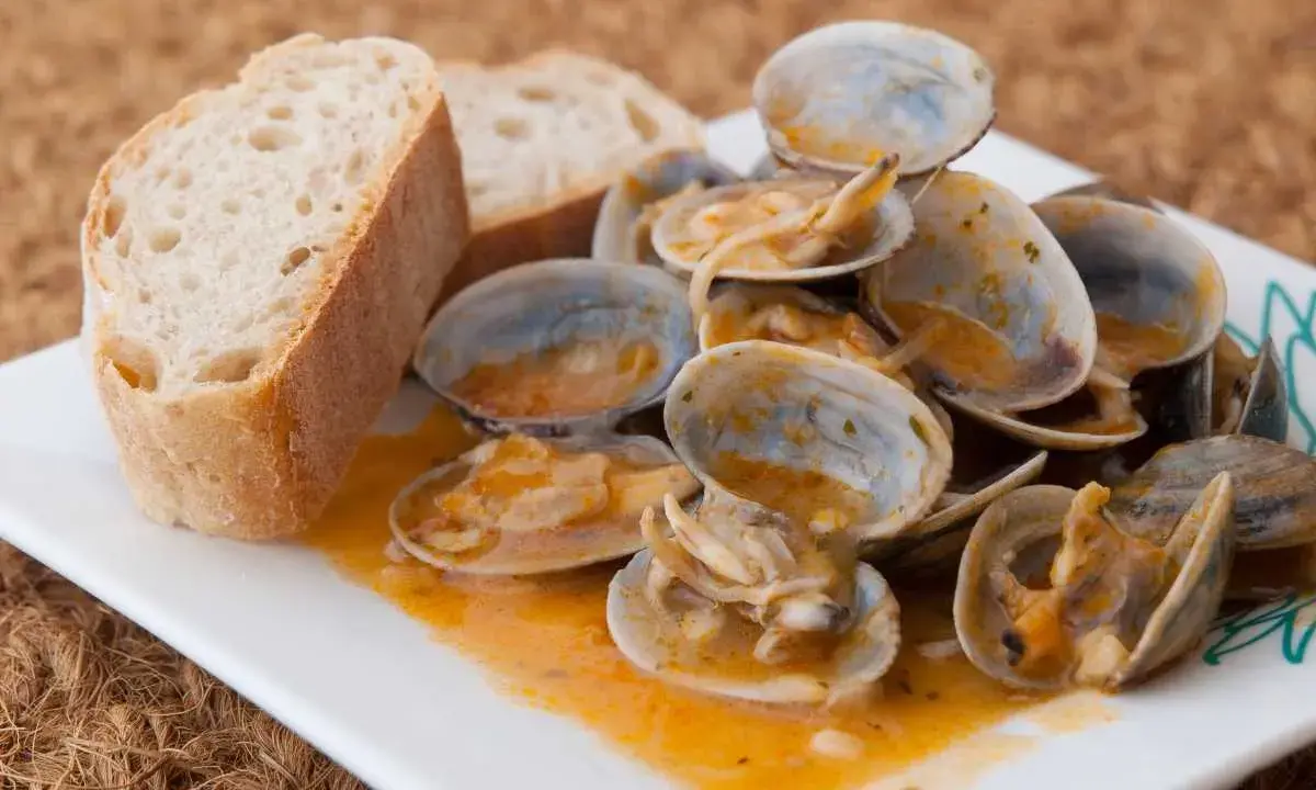 Almejas a la marinera, jugosas y sabrosas, servidas con pan rústico para mojar en la deliciosa salsa.