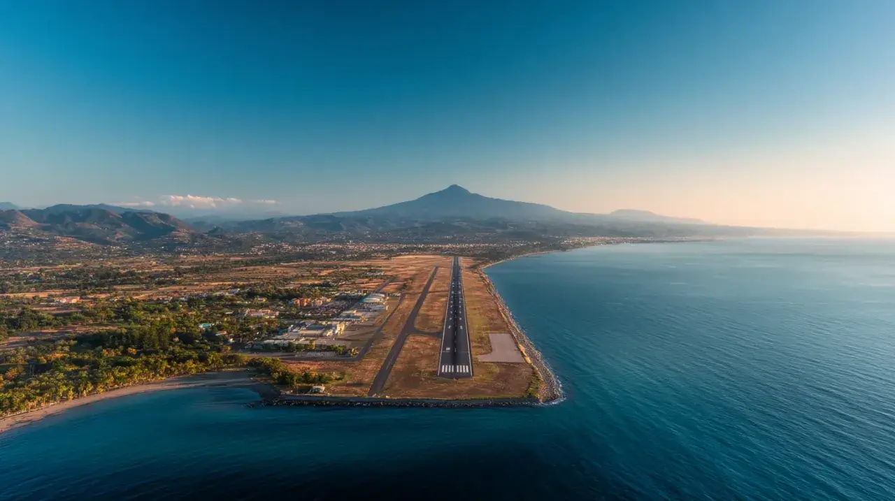 Flygplats vid havet med berg i bakgrunden. En landningsbana sträcker sig ut mot vattnet, en vy som påminner om Palermo flygplats.