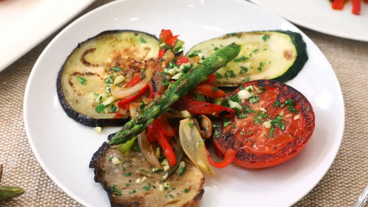 Deliciosa parrillada de verduras con berenjena, calabacín, tomate, pimientos y espárragos, todo aderezado con ajo y perejil.