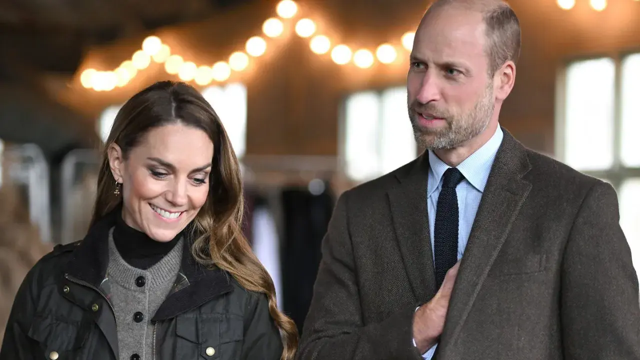 Prins William av Wales och Kate Middleton ler under en ljusslinga.