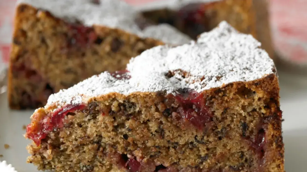 Ein saftiges Stück Buchweizentorte mit Preiselbeeren, bestäubt mit Puderzucker.