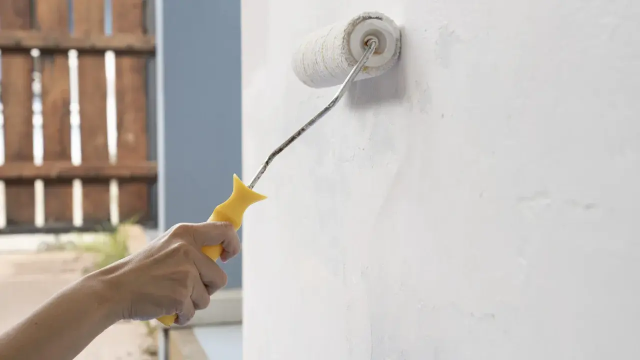 Mano aplicando imprimación a paredes con rodillo. Preparando la superficie para pintar.
