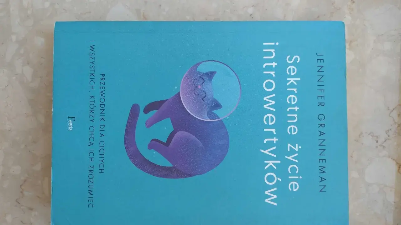 Książka "Sekretne życie introwertyków" z kotem w hełmie kosmicznym. Przewodnik dla cichych i tych, którzy chcą ich zrozumieć.