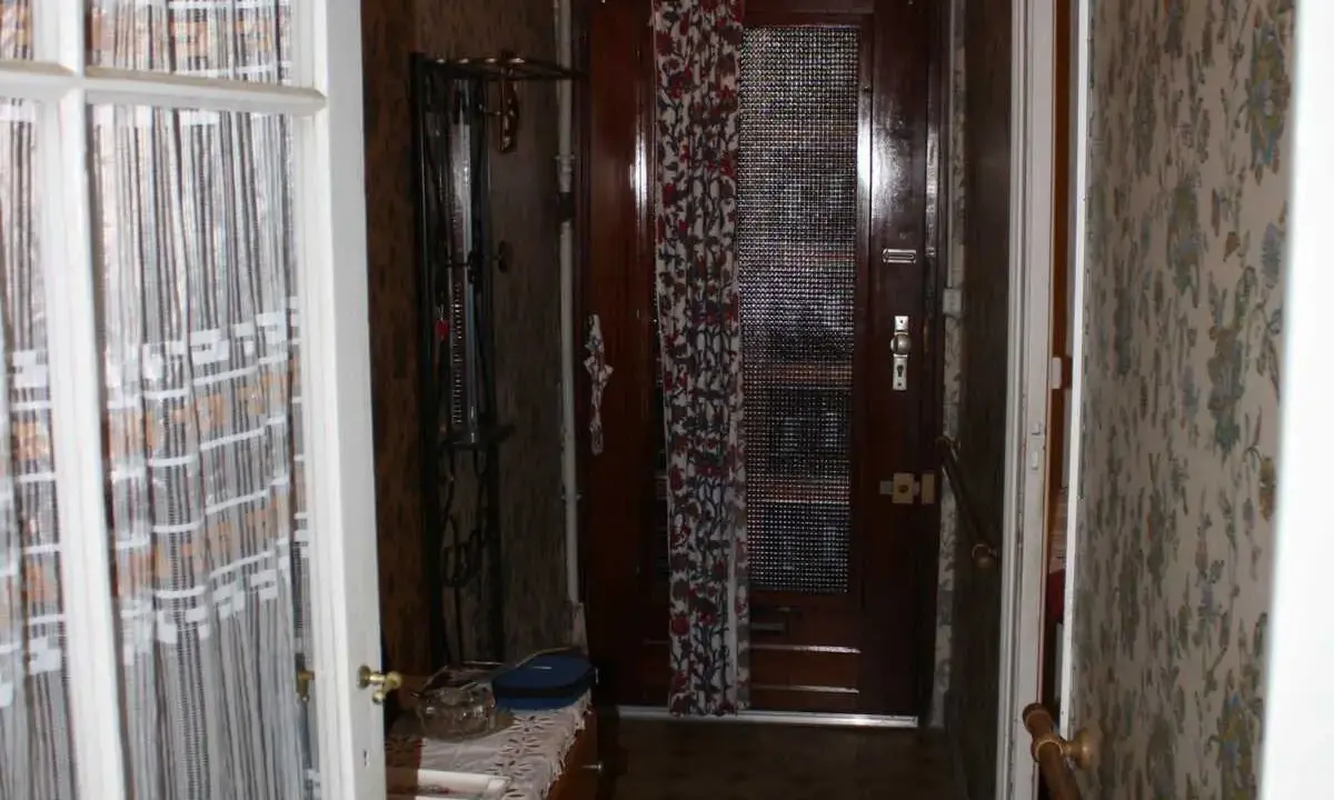 Couloir d'une maison bordeaux typique, avec une porte en bois, un porte-manteau et un papier peint fleuri.