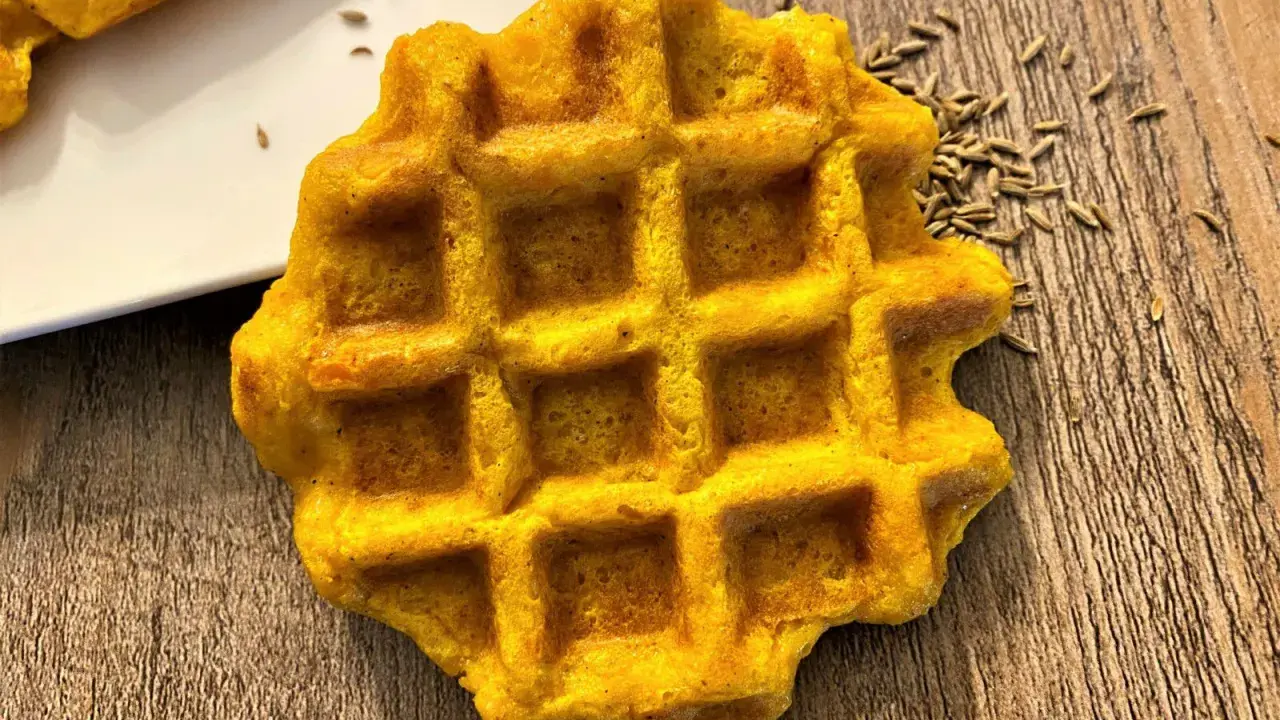 Gaufre carotte dorée, parsemée de graines sur fond de bois. Un délice orangé à déguster.