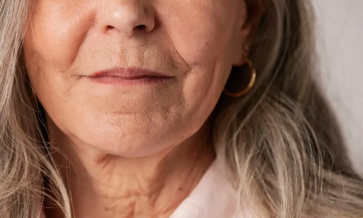 Gros plan sur le visage d'une femme âgée, montrant les rides autour de la bouche et du cou. Des conseils sur comment faire disparaître les rides profondes pourraient être utiles.