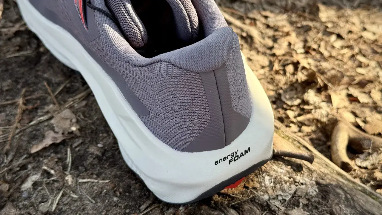 Szary but Salomon Ultra Glide 3 z białą podeszwą i napisem "energy FOAM" na tle leśnej ściółki.