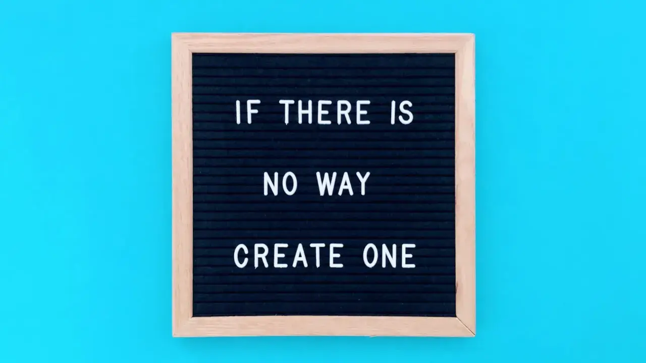 Czarna tablica z białym napisem "IF THERE IS NO WAY CREATE ONE" na niebieskim tle.