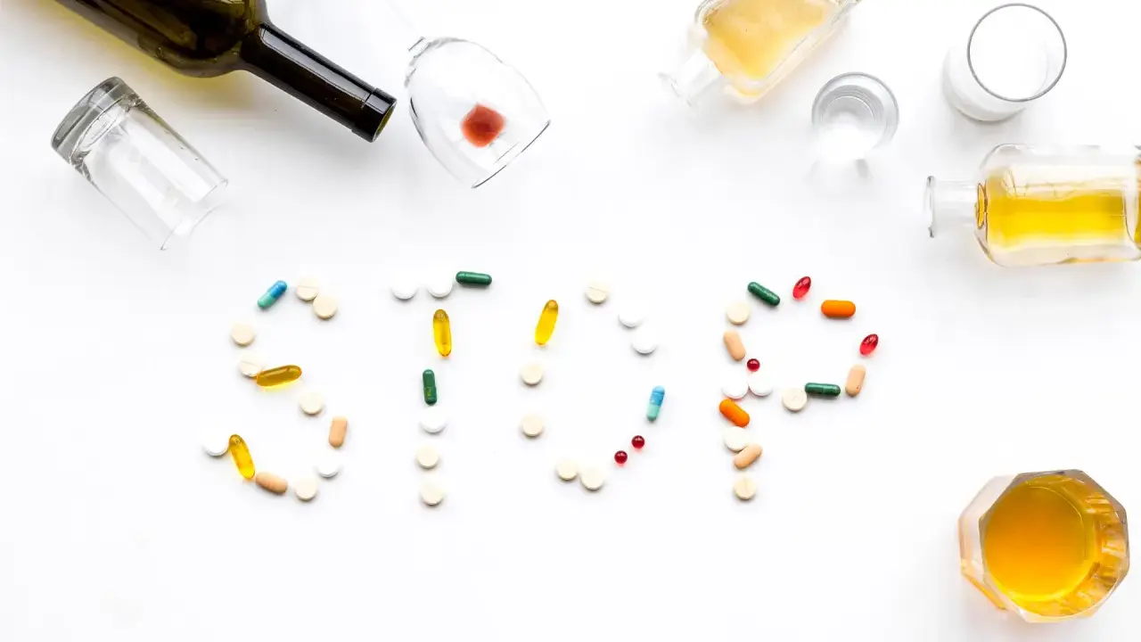 Nalewki, kieliszki i tabletki tworzą napis STOP. Różne rodzaje alkoholizmu i leczenia.