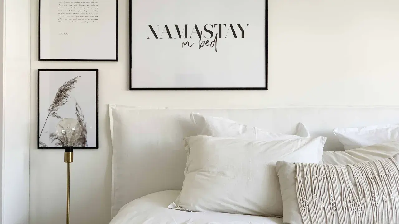 Un lit douillet avec une tête de lit DIY, des coussins texturés et des cadres muraux inspirants.