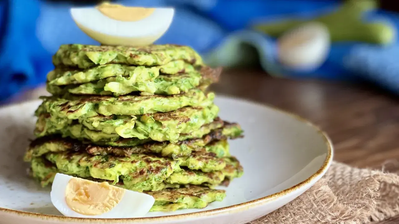 Pila di rosti di zucchine dorati, guarniti con spicchi di uovo sodo. Un piatto leggero e gustoso.