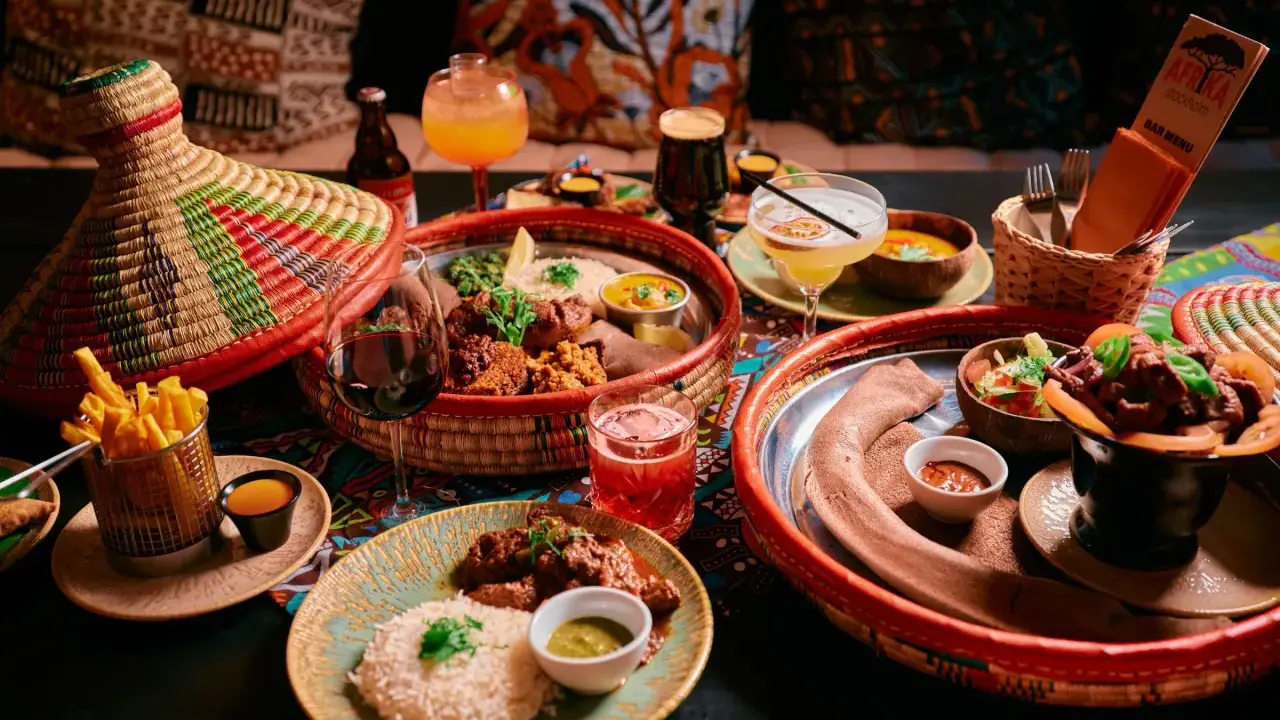 En härlig måltid på en afrikansk restaurang med flera rätter, drycker och en färgglad duk.