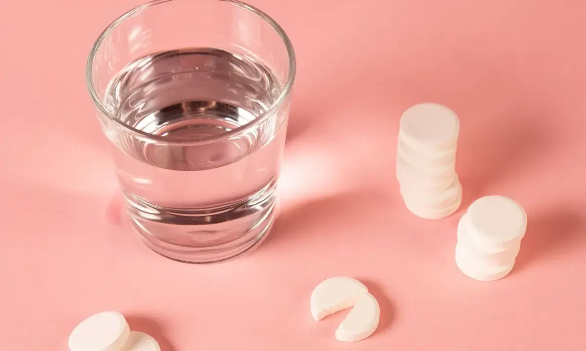 Ein Glas Wasser und Magnesium-Brausetabletten auf rosa Untergrund. Hilft Magnesium beim Einschlafen?