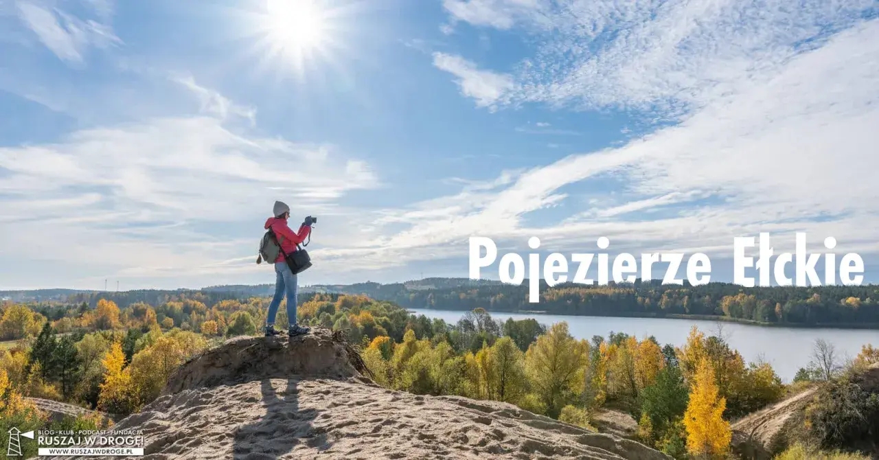 Idealne miejsce na weekend: dziewczyna z aparatem na wydmie podziwia jesienne krajobrazy nad Jeziorem Ełckim.