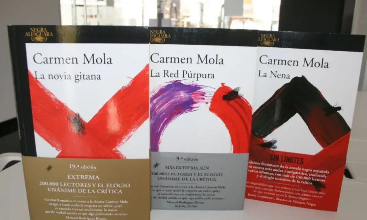 Libri di Carmen Mola: "La novia gitana", "La Red Púrpura" e "La Nena". Copertine con disegni astratti e mosche.