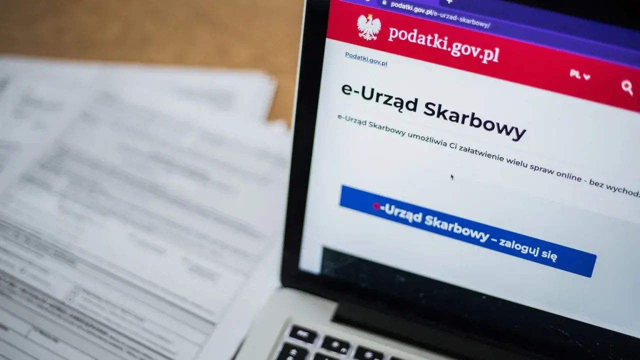 Na ekranie laptopa widoczny jest portal e-Urząd Skarbowy. Obok leżą dokumenty, które mogą zawierać identyfikator zobowiązania.