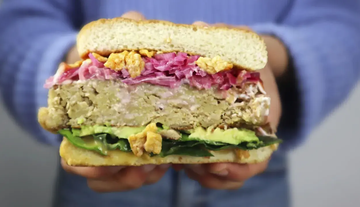Hamburguesa de pollo con aguacate, col morada y crujientes trozos. ¡Una delicia!