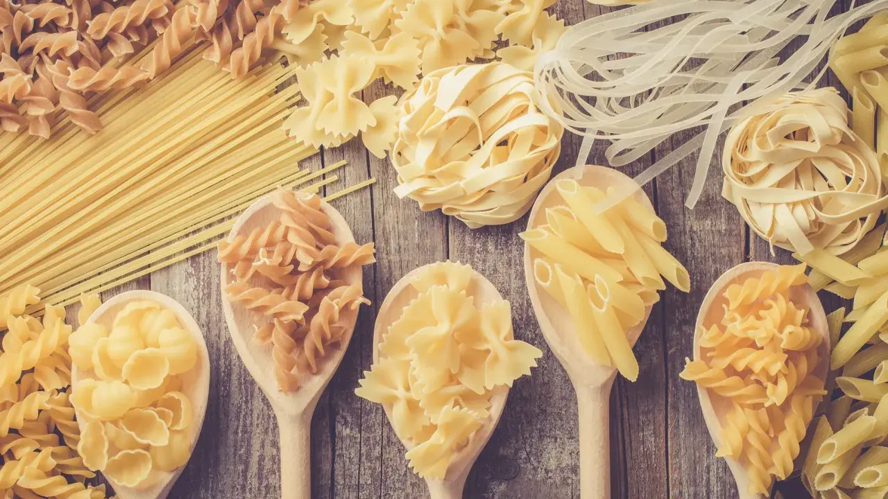 Verschiedene Nudelsorten auf Holzlöffeln und Holzuntergrund. Welche Pasta hat am wenigsten Kalorien? Vielleicht die dünnen Reisnudeln?