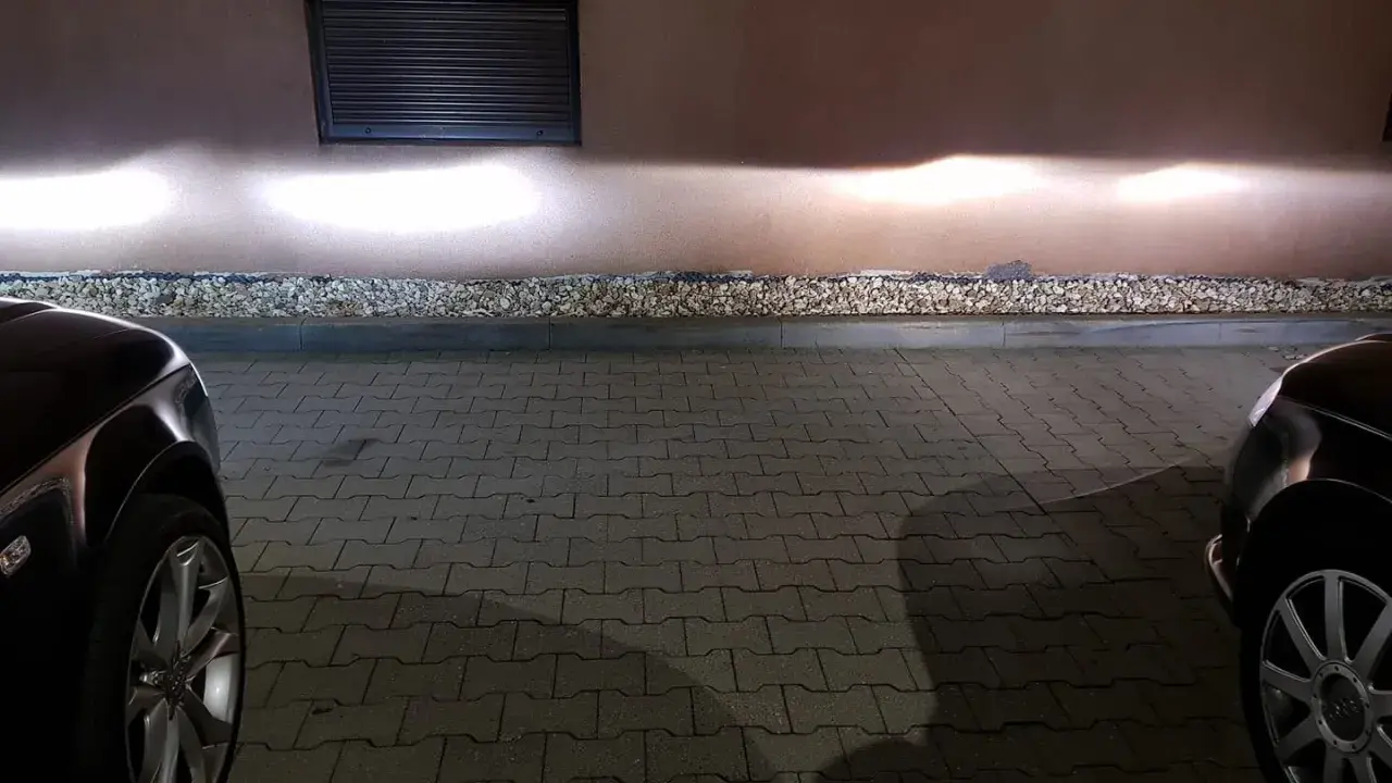 Jasne światła z przodu Audi A4 B6 oświetlają ścianę.