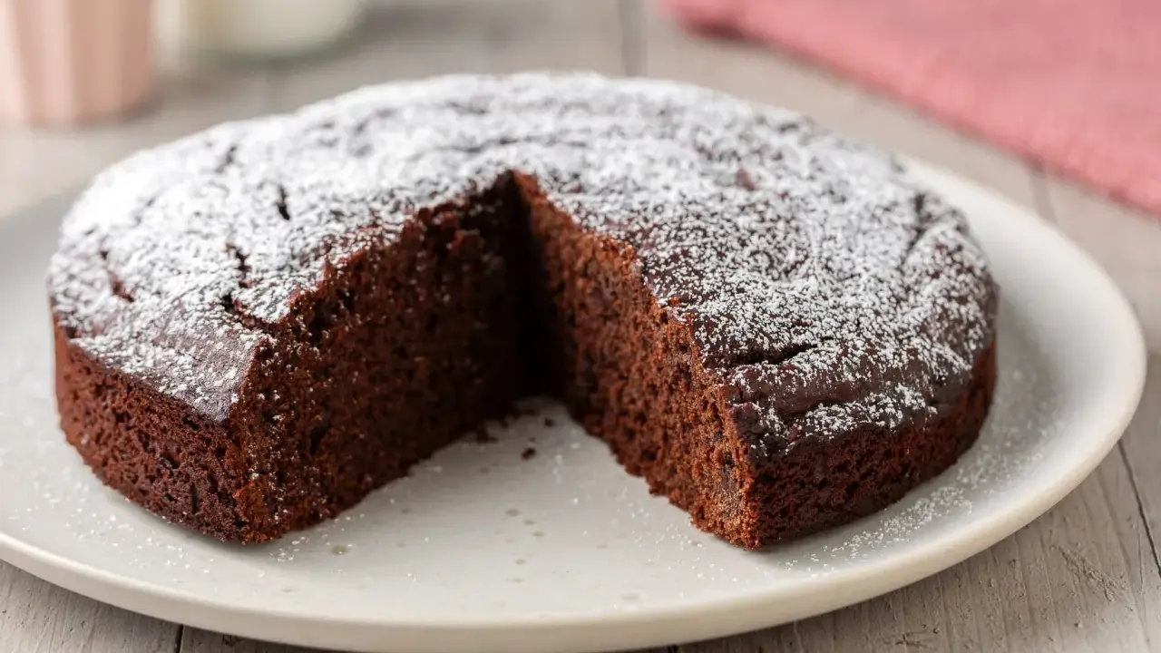 Una deliziosa torta al cioccolato, spolverata di zucchero a velo, con una fetta mancante, pronta per essere gustata.