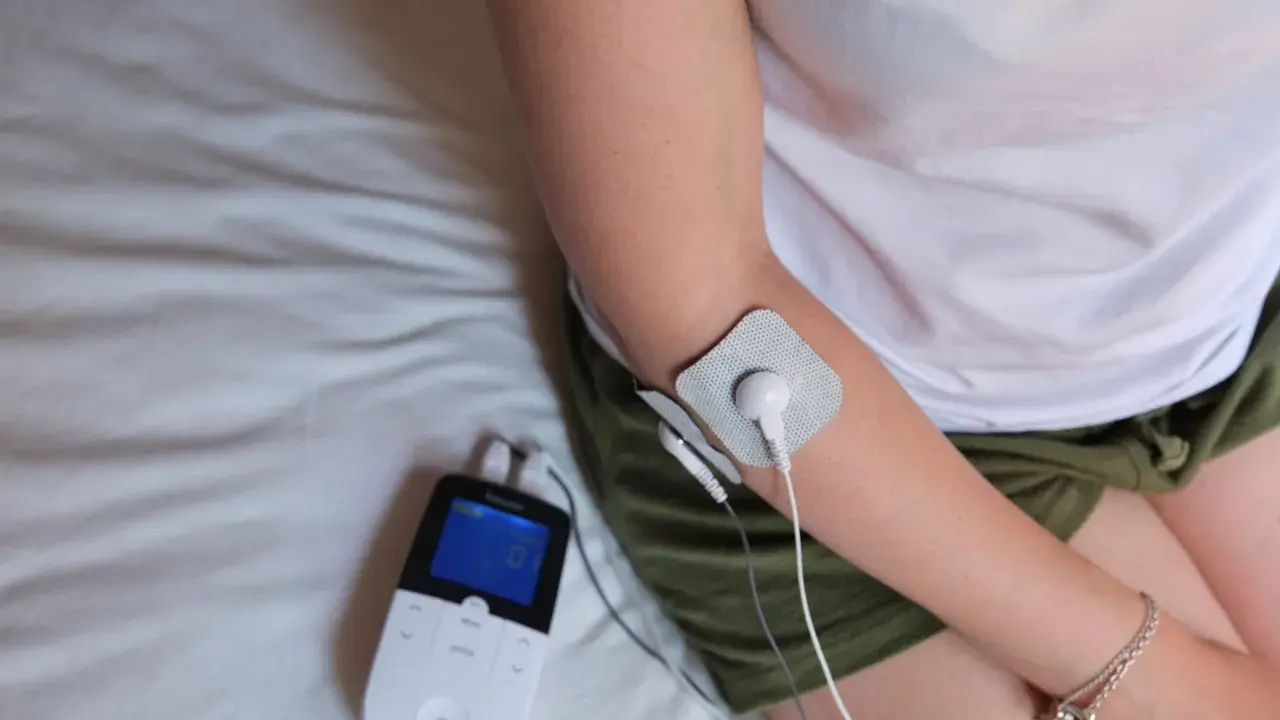Traitement d'une épicondylite, maladie professionnelle, avec un appareil d'électrostimulation sur le bras.