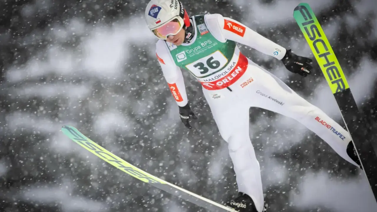Skoczek narciarski w locie, przygotowuje się do lądowania. Widoczny numer 36. To może być zapowiedź skoki narciarskie 2026.