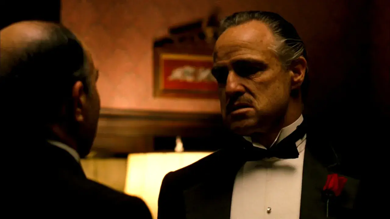 Marlon Brando nei panni di Don Corleone, un'icona de "Il Padrino", in una scena che riassume la sua recensione: potere e dramma.