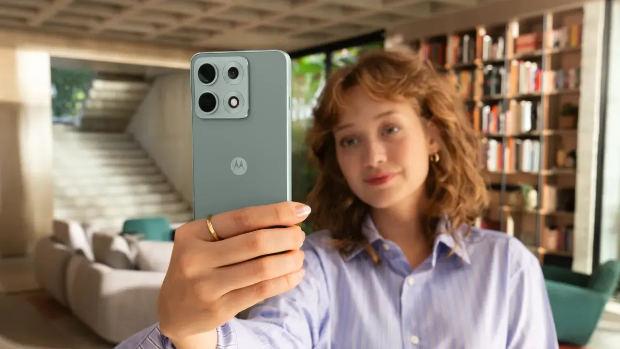 Kobieta robi selfie telefonem Motorola E6 Play w nowoczesnym wnętrzu.