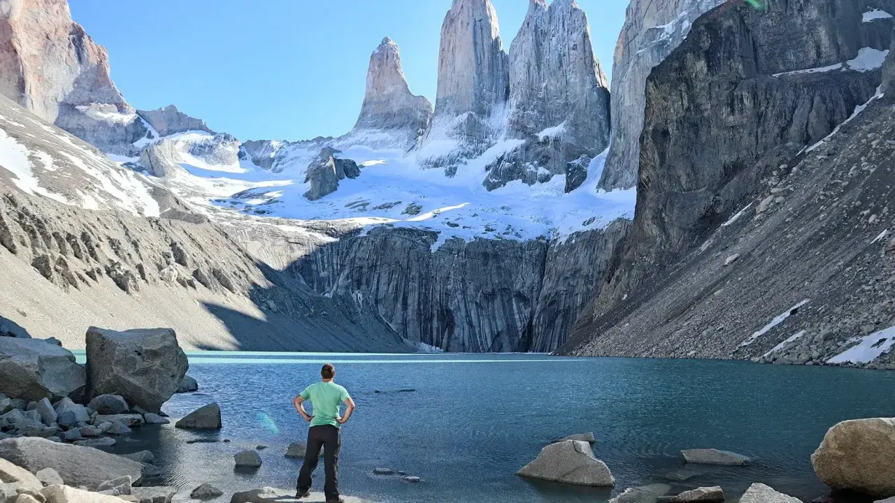 Widok na majestatyczne Torres del Paine w Chile. Turysta podziwia turkusowe jezioro i ośnieżone szczyty.