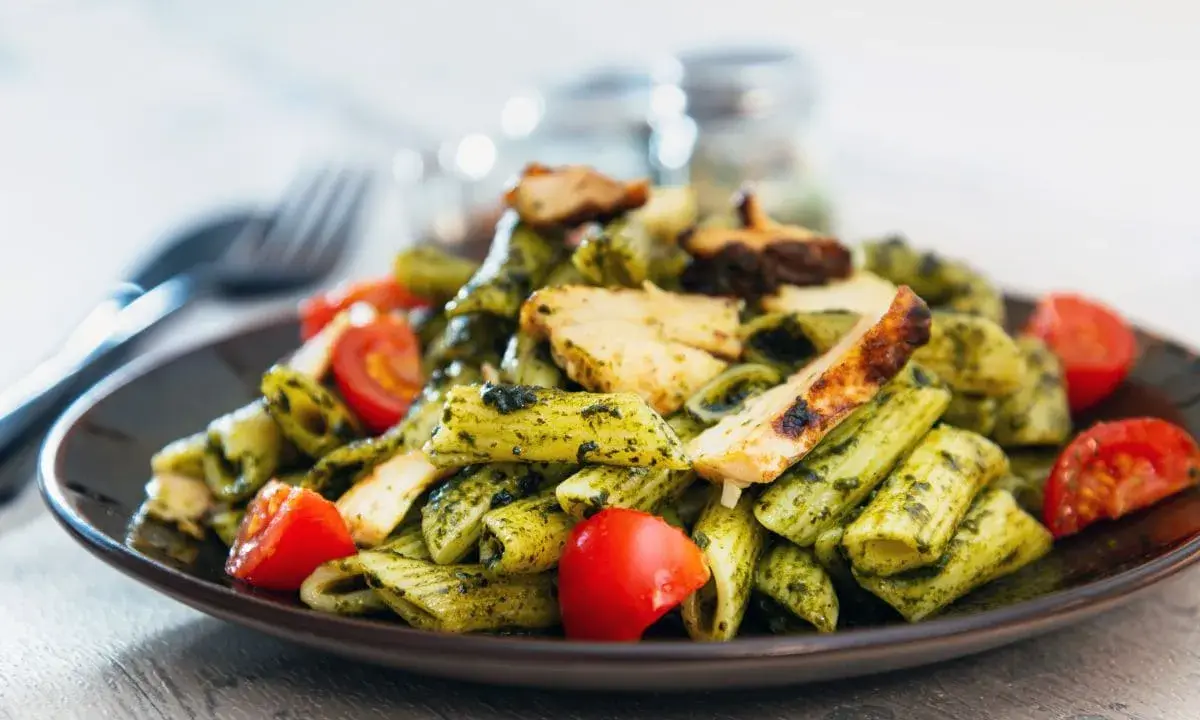 Penne z kurczakiem i pomidorkami, obficie polane aromatycznym makaronem z pesto bazyliowym. Pyszny obiad gotowy!