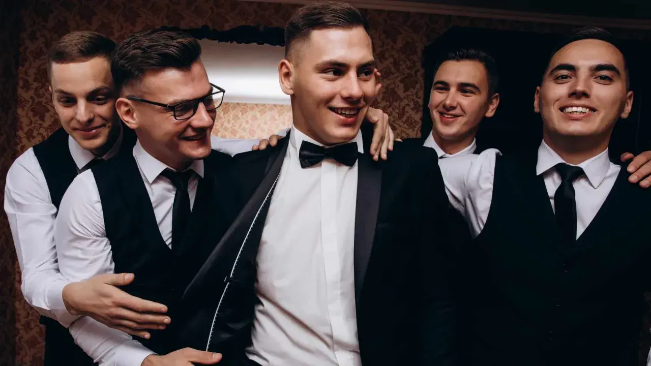 Uśmiechnięci panowie w garniturach, przygotowujący się na ekstremalny wieczór kawalerski.