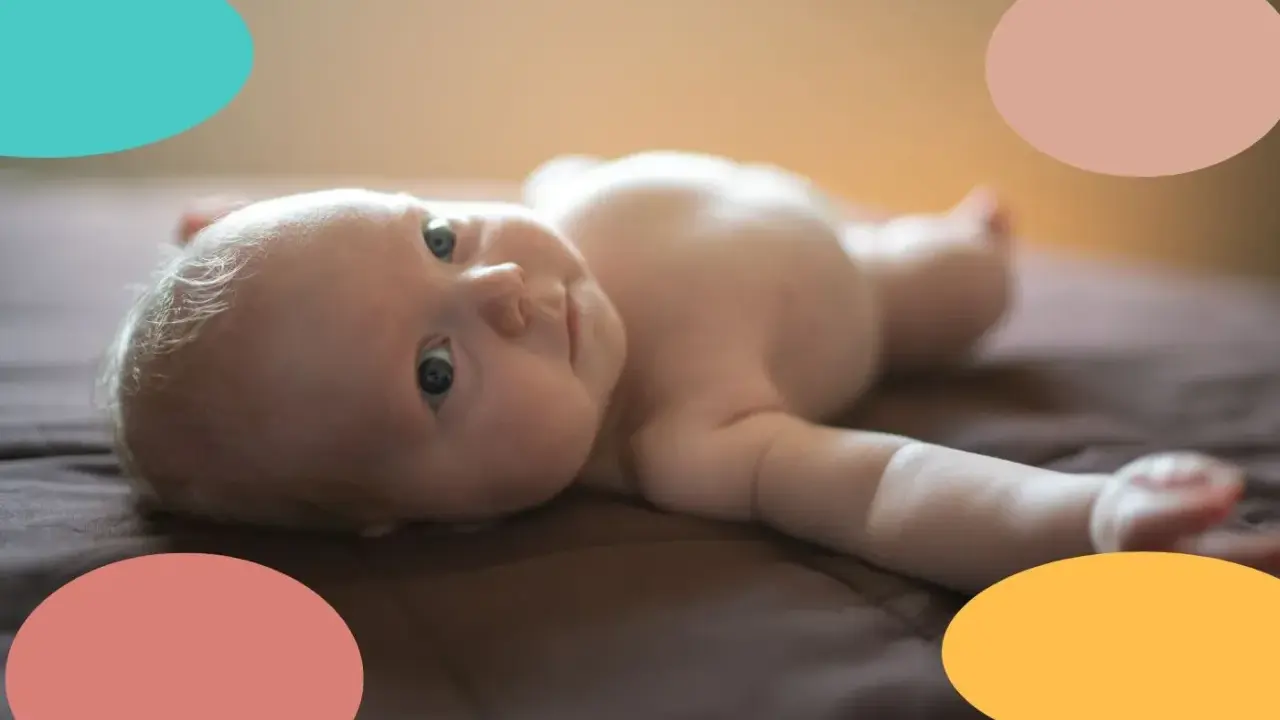 Un bebé de 2 meses, con ojos curiosos, yace boca arriba. Parece que este pequeño no duerme, ¡sus ojitos están bien abiertos!