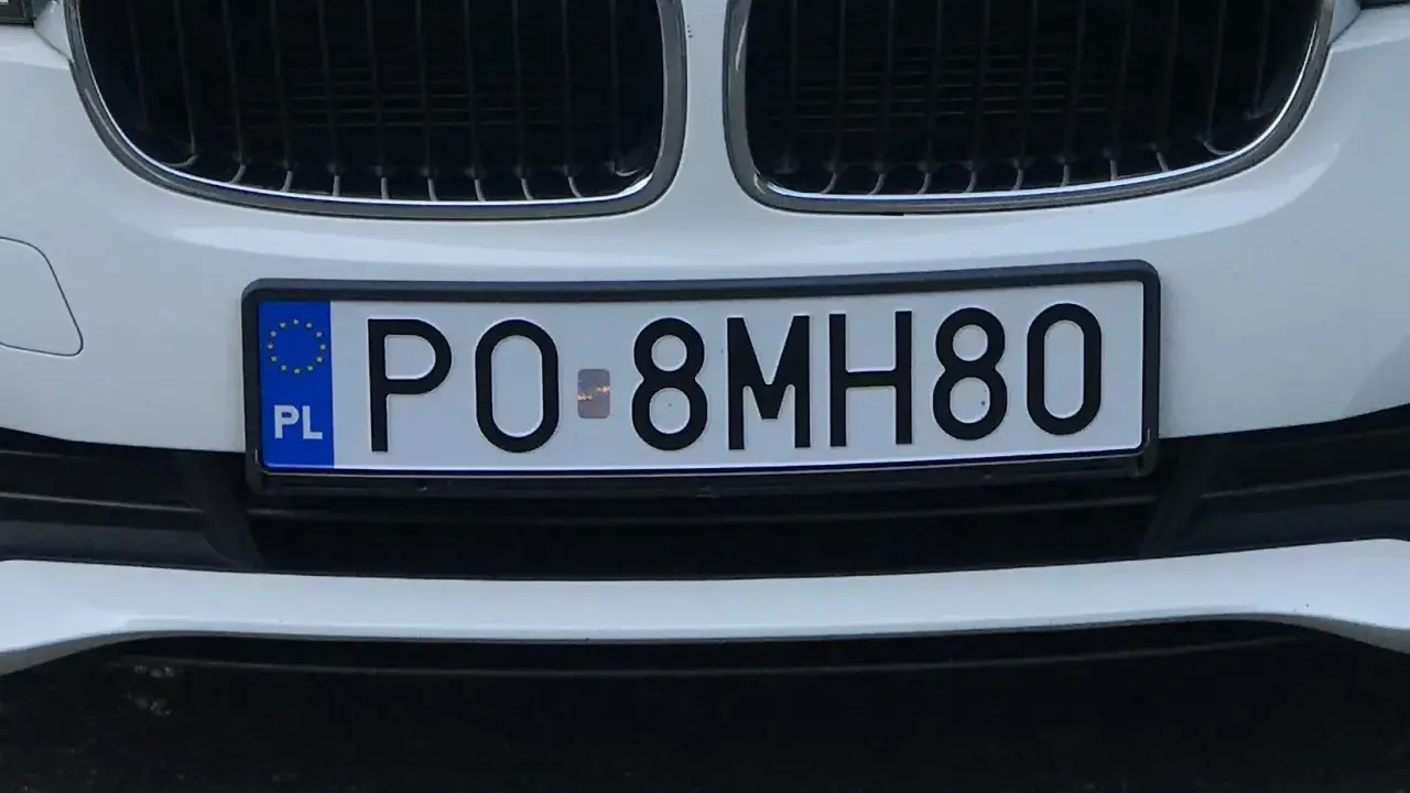 Biały samochód z tablicą rejestracyjną PO-8MH80.