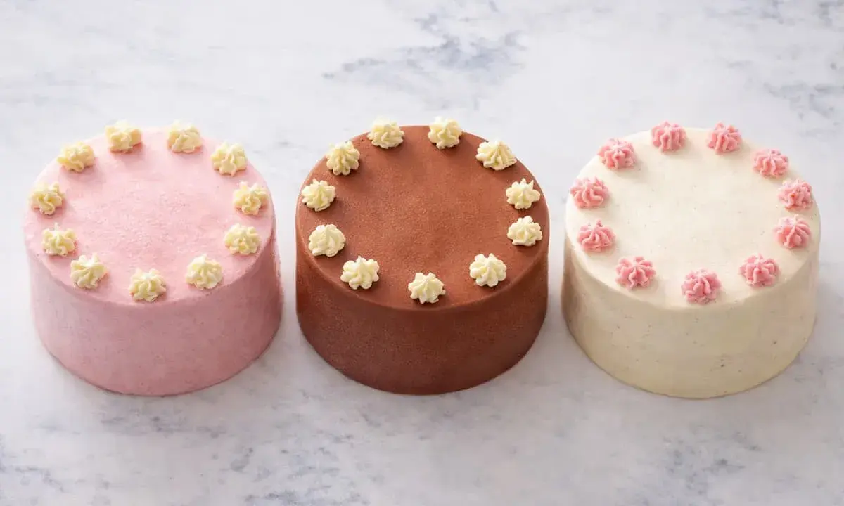 Trois petits gâteaux décorés, parfaits pour une recette de bento cake. Un rose, un chocolat, un vanille.