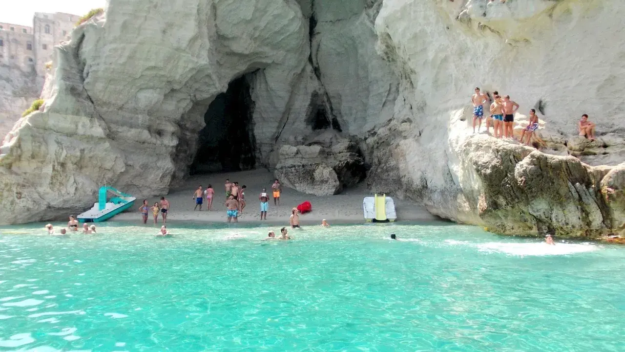 Bambini e adulti si divertono nella grotta del Palombaro, tra scogli e acque cristalline.
