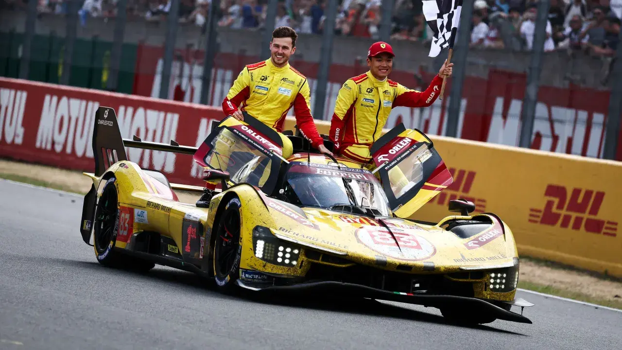 Zwei Rennfahrer in gelb-roten Overalls jubeln neben ihrem gelben Ferrari Le Mans Prototyp mit der Startnummer 83.