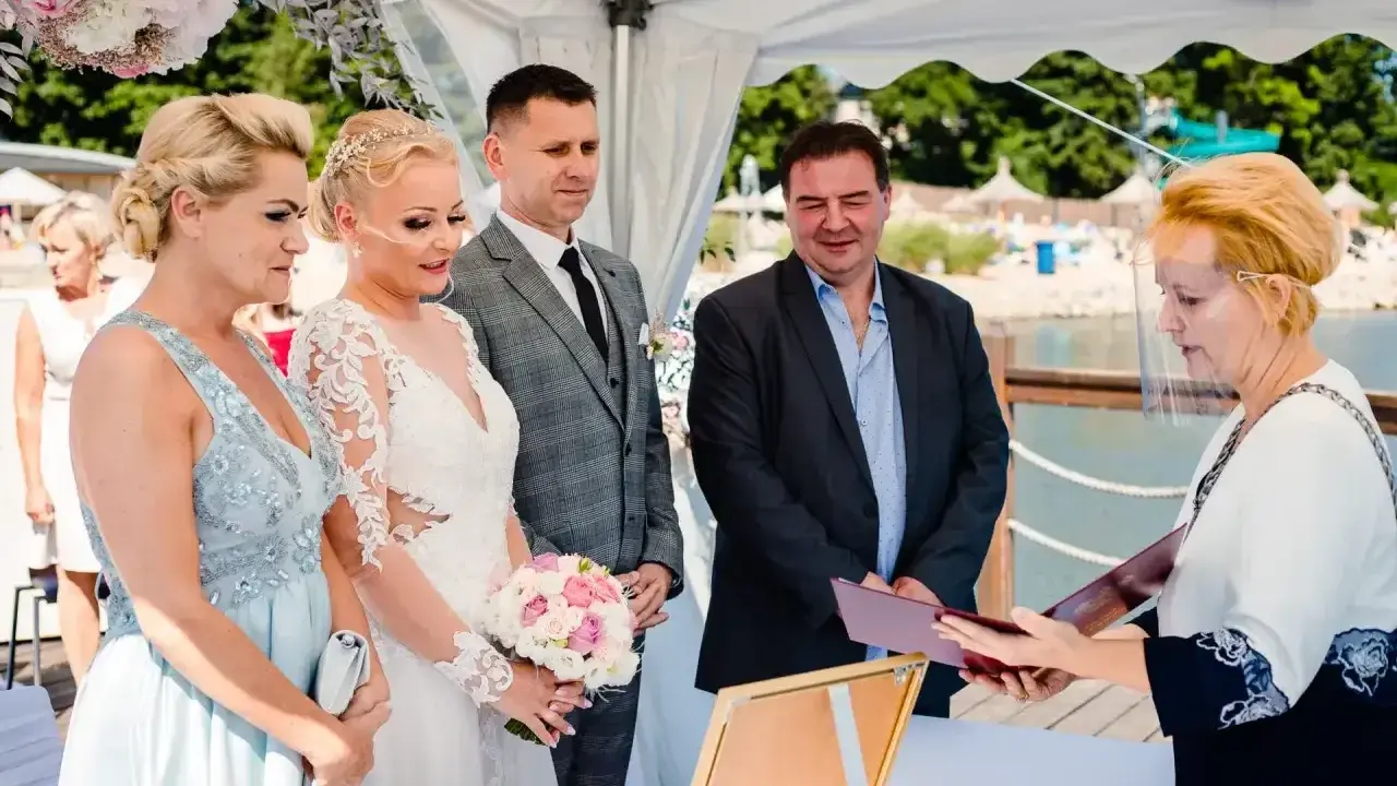 Ślub cywilny po rozwodzie. Para młoda, świadkowie i urzędniczka podczas ceremonii nad wodą.