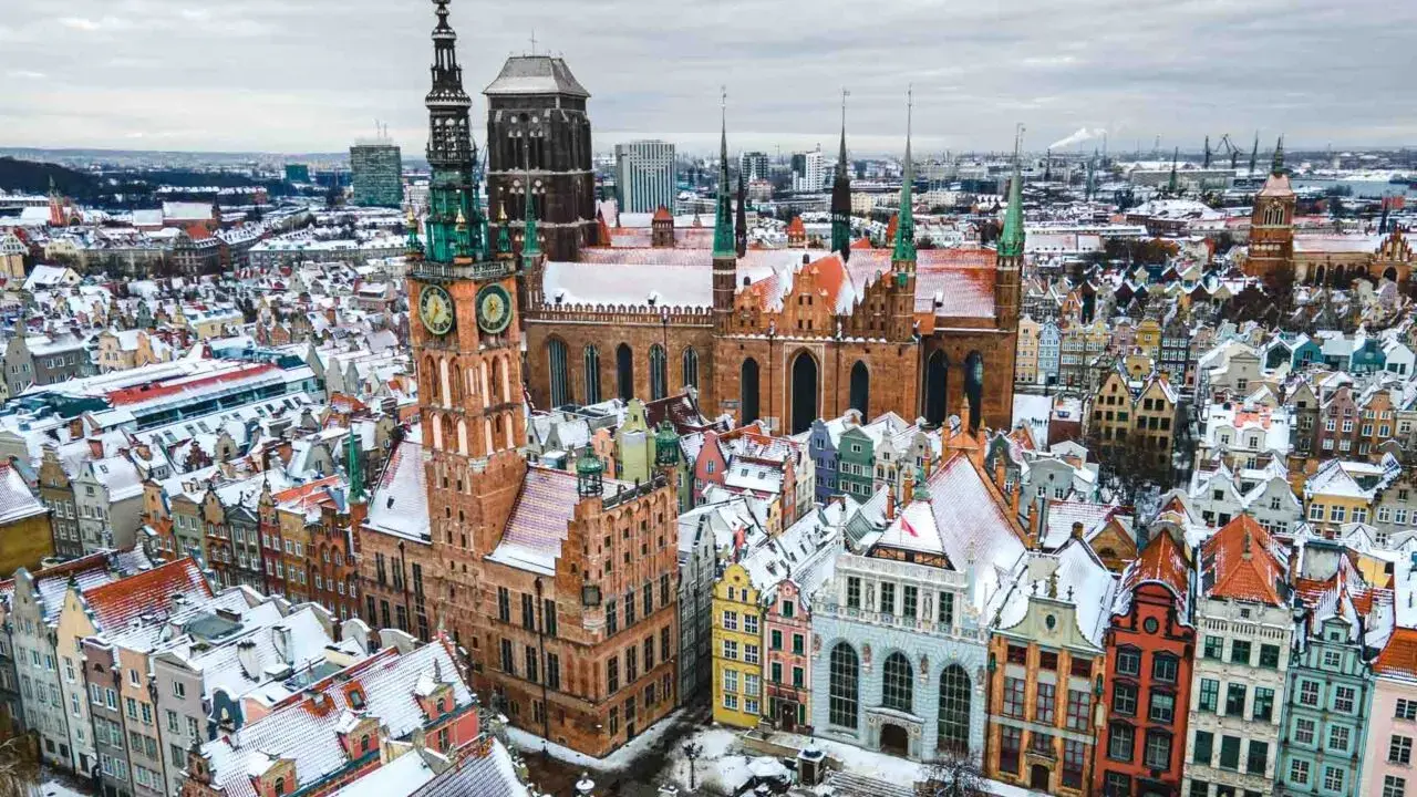 Zimowy widok na Gdańsk. Ratusz Głównego Miasta i Bazylika Mariacka w śniegu. Wspaniałe gdańskie atrakcje turystyczne.