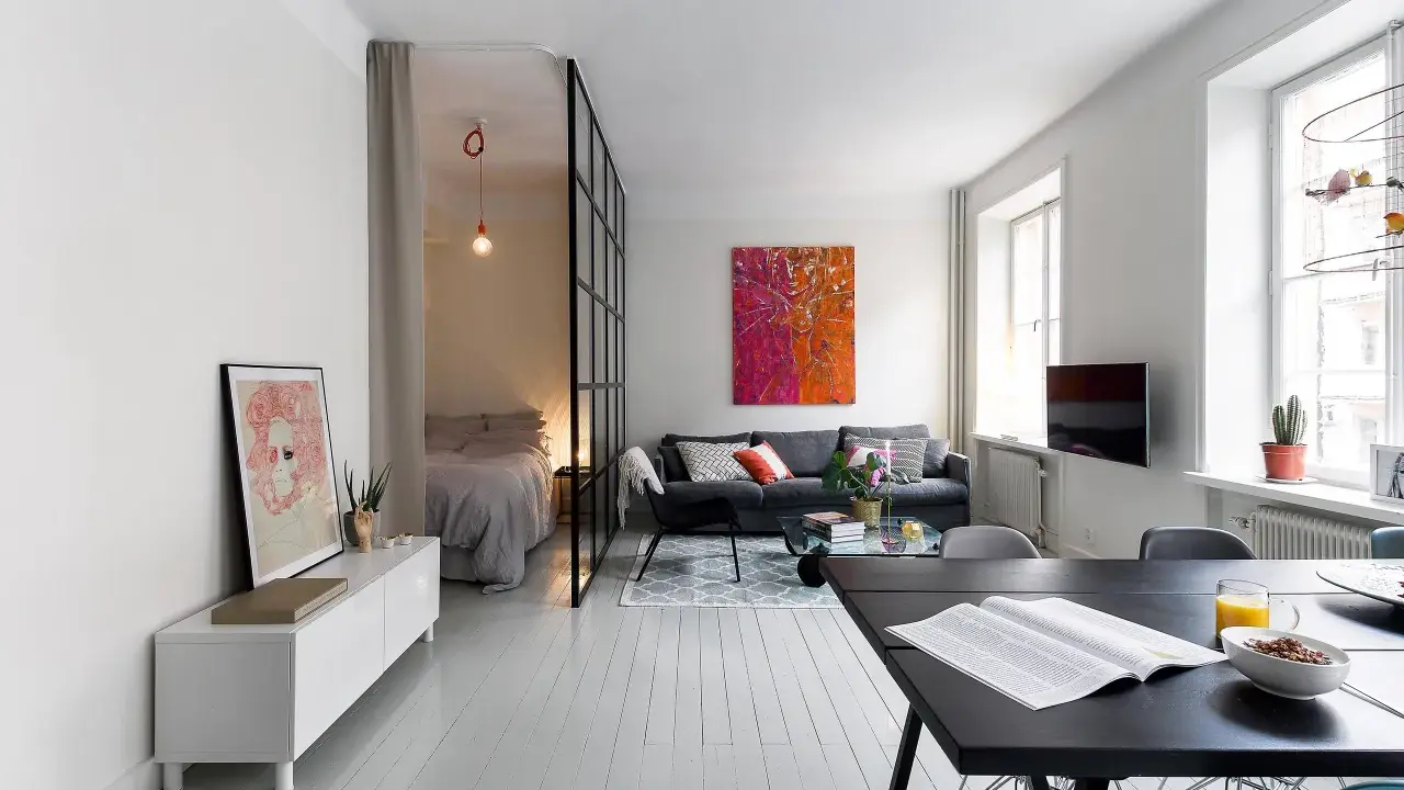 Smart lösning för att bo på liten yta. Sovrummet avskiljs med en glasvägg. Vardagsrummet har en soffa och ett soffbord.