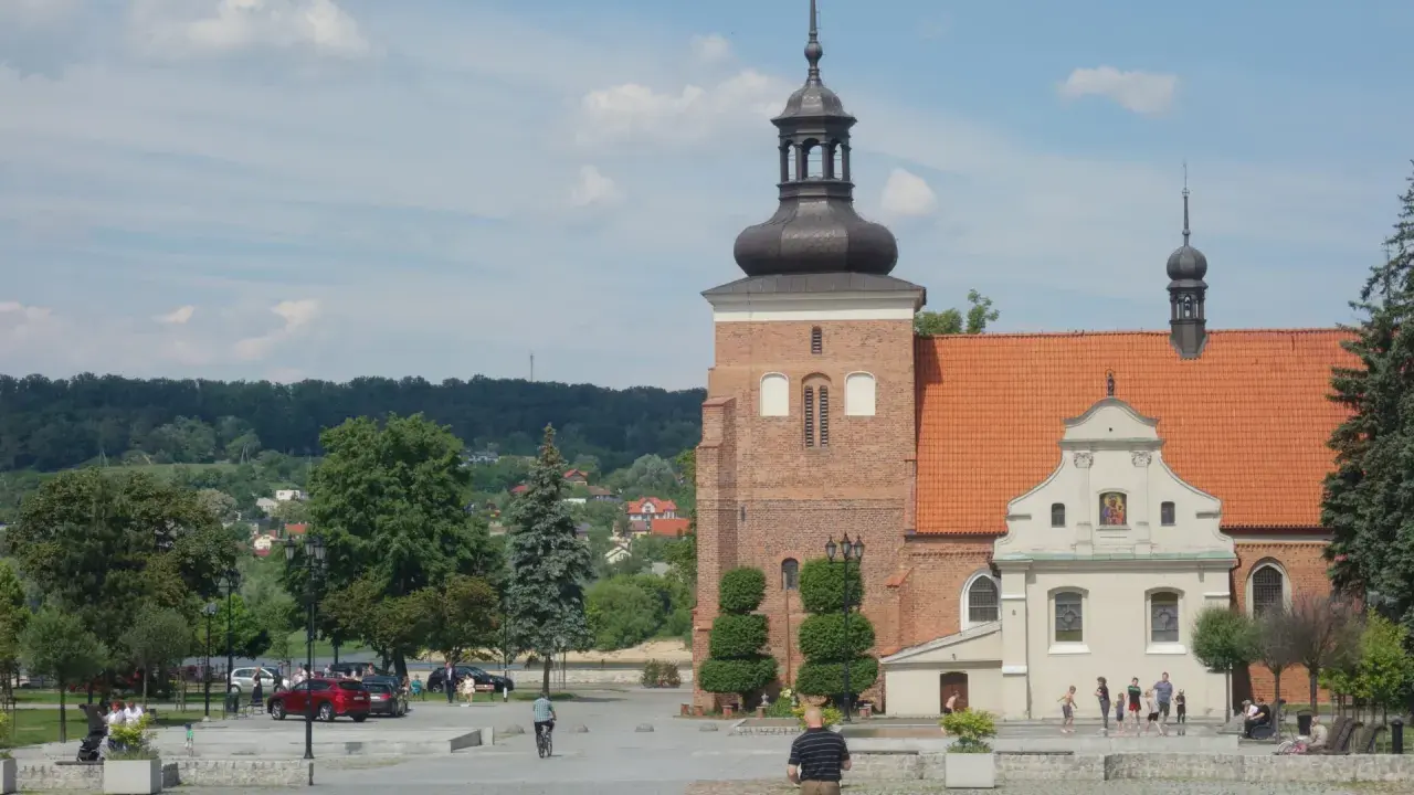 Włocławek stare miasto: plac z kościołem, wieżą i ludźmi spacerującymi w słoneczny dzień.