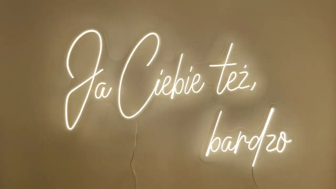 Neonowy napis "Ja ciebie też bardzo" rozświetla ścianę, tworząc ciepłą atmosferę.