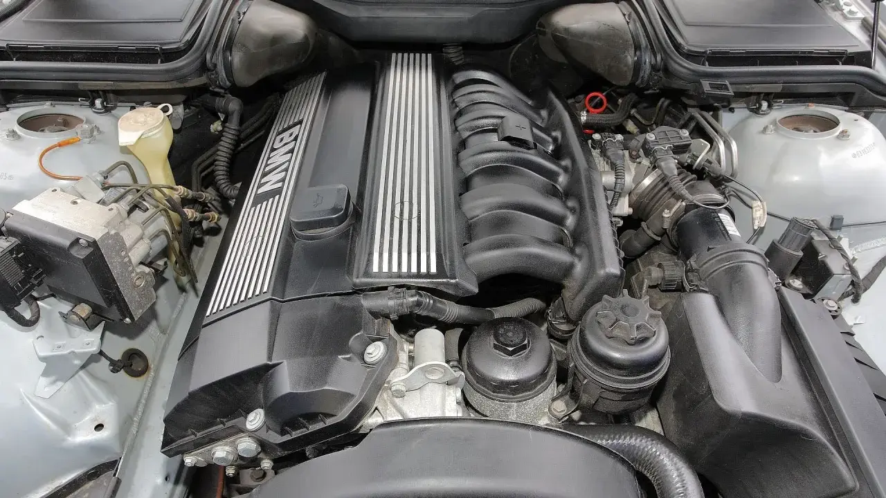 Silnik BMW E39, prawdopodobnie V8, z widocznym kolektorem dolotowym i osłoną zaworów z napisem BMW.
