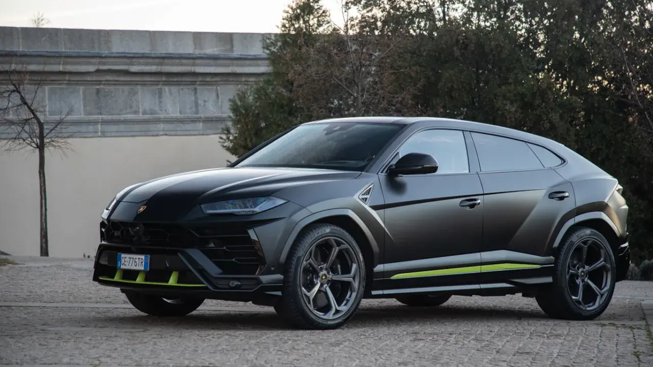 Un imponente **lamborghini urus negro** se exhibe con detalles en verde lima, posado sobre un camino empedrado.