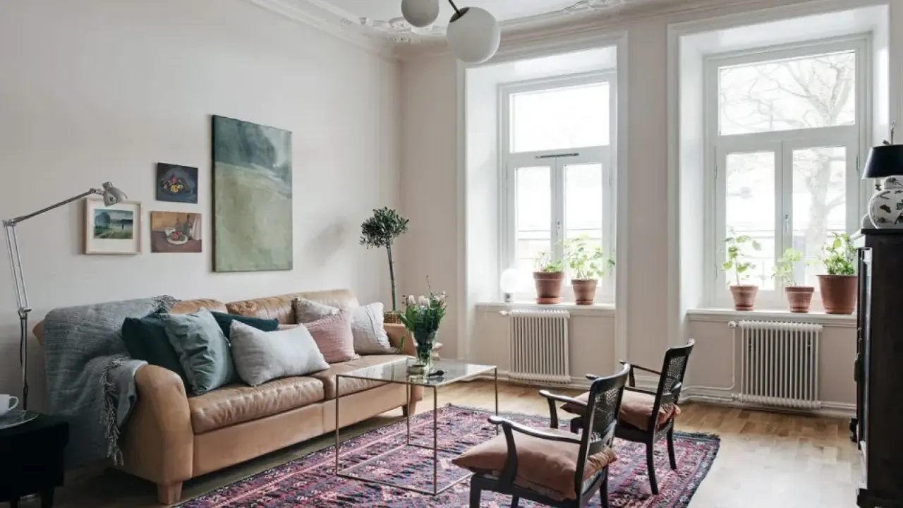 En vardagsrumsinredning som visar vad bohemisk betyder: en brun skinnsoffa, en stor mönstrad matta, konst och växter.