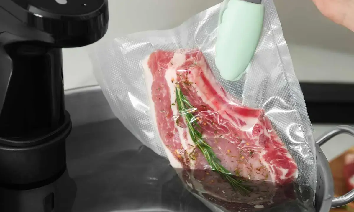 Ein Steak mit Rosmarin und Gewürzen wird für das Suvid Garen in einen Vakuumbeutel gelegt.
